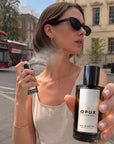 Woman applying OPUX perfume outdoors